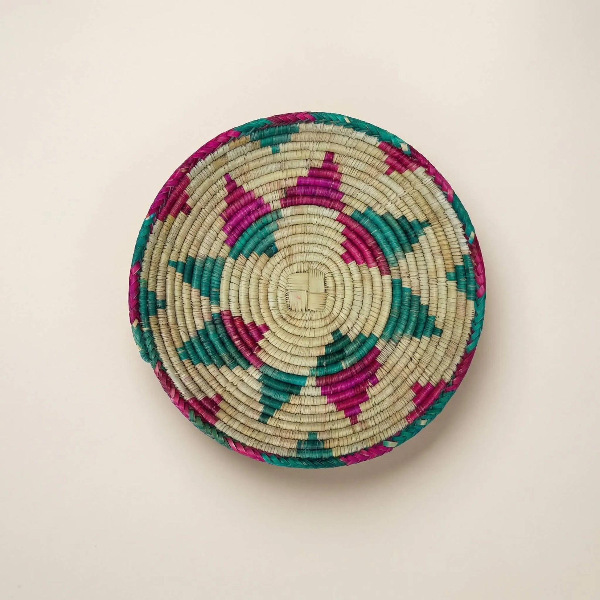 Detailed overhead view of the SHKOR signature plate showing the intricate sunburst weave and natural sage-tan fibers.