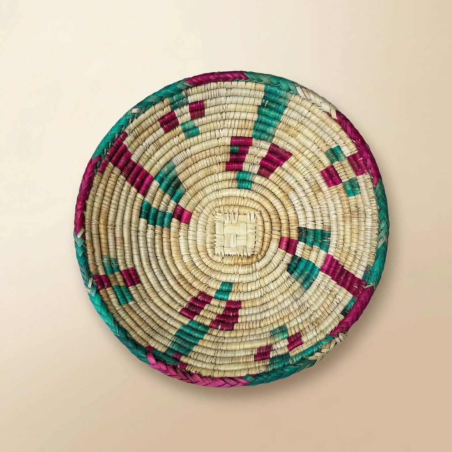 Detailed top view of the SHKOR signature plate showing intricate hand-woven Mazari palm patterns in fuchsia and teal.