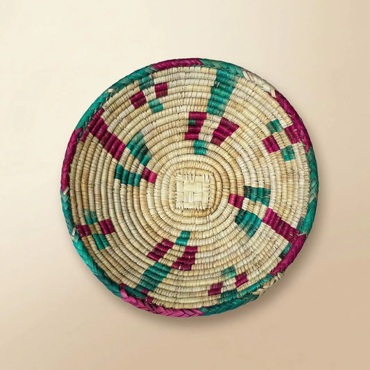 Detailed top view of the SHKOR signature plate showing intricate hand-woven Mazari palm patterns in fuchsia and teal.