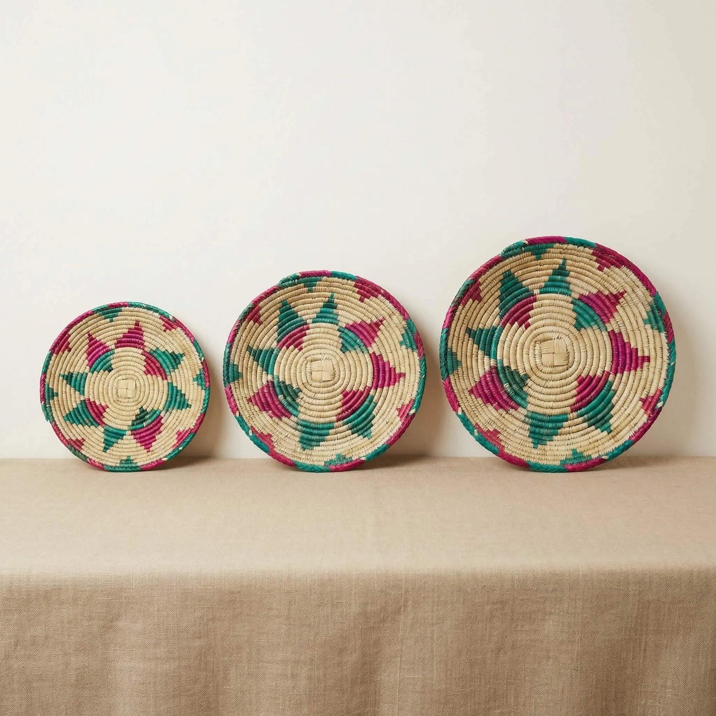 A collection of SHKOR Signature plates in small, medium, and large sizes showing teal and fuchsia geometric patterns.